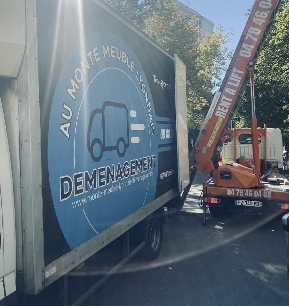 Camion de déménagement "Au Monte Meuble Lyonnais" avec logo et monte-meuble orange "Rent a Lift". Tél : 04 78 46 04 08.